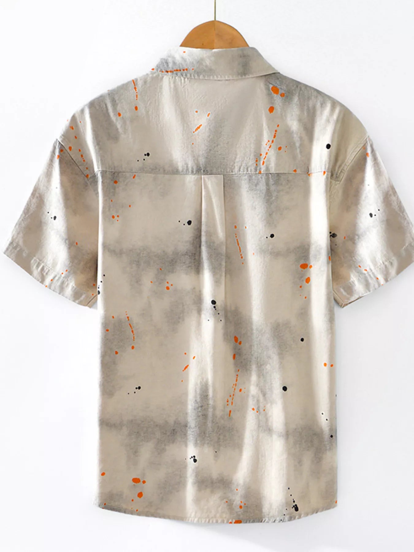 Beige shirt with abstract pattern on a hanger against a white background