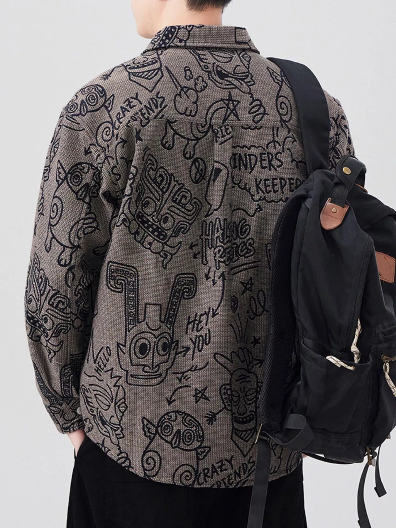 Person wearing a patterned shirt with a black backpack on a plain background