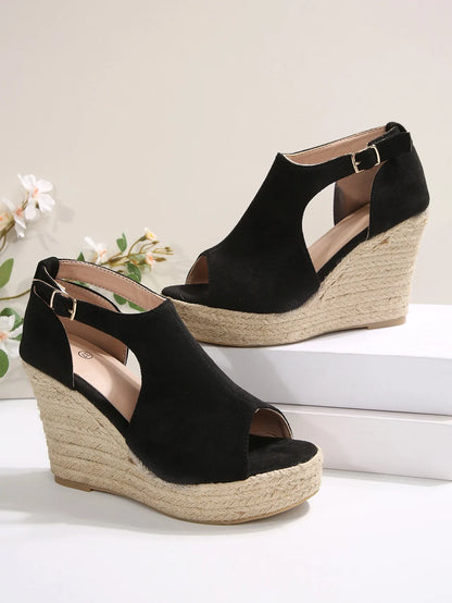 Black wedge sandals with espadrille soles on a light background