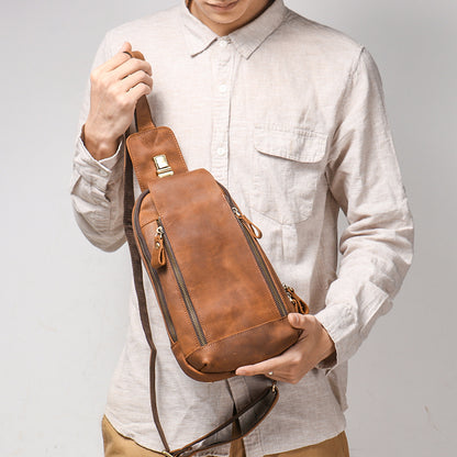 Person holding a brown leather sling bag against a plain background