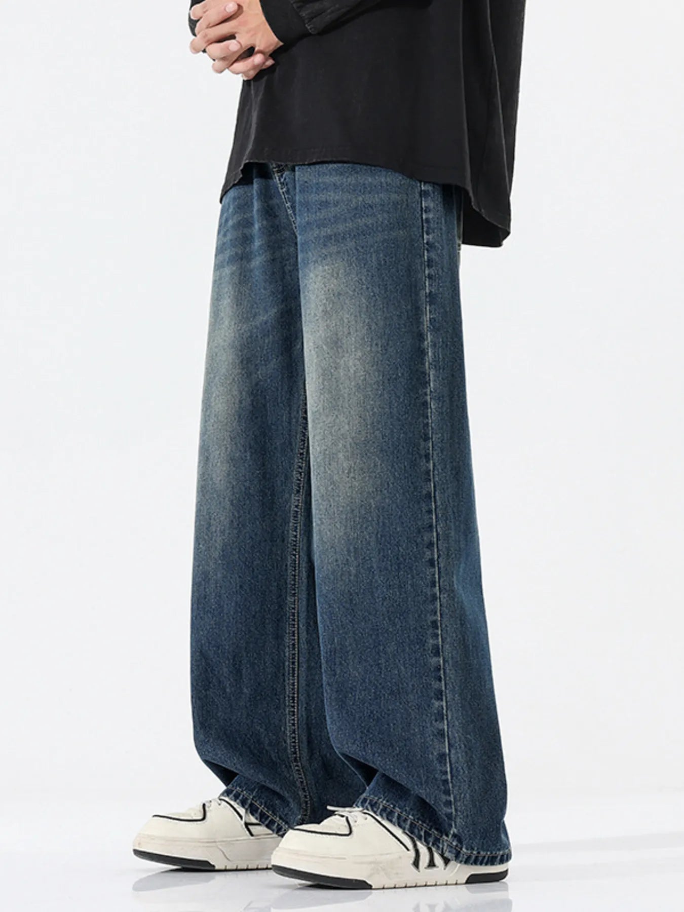 Person wearing wide-leg jeans and white sneakers on a white background