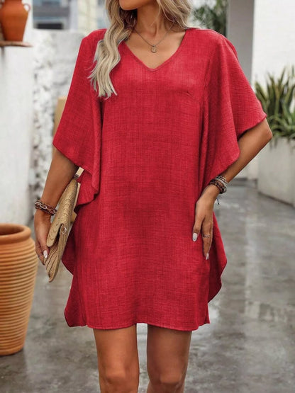 Woman wearing a red dress with a blurred outdoor background