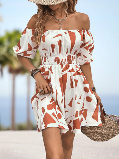 Woman in a red and white patterned dress on a beach with palm trees in the background