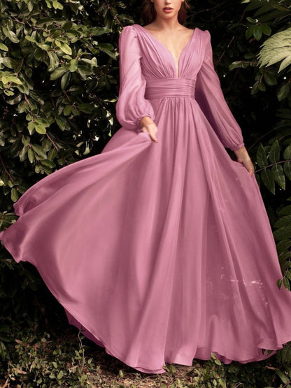 Woman wearing a long pink dress standing among green foliage