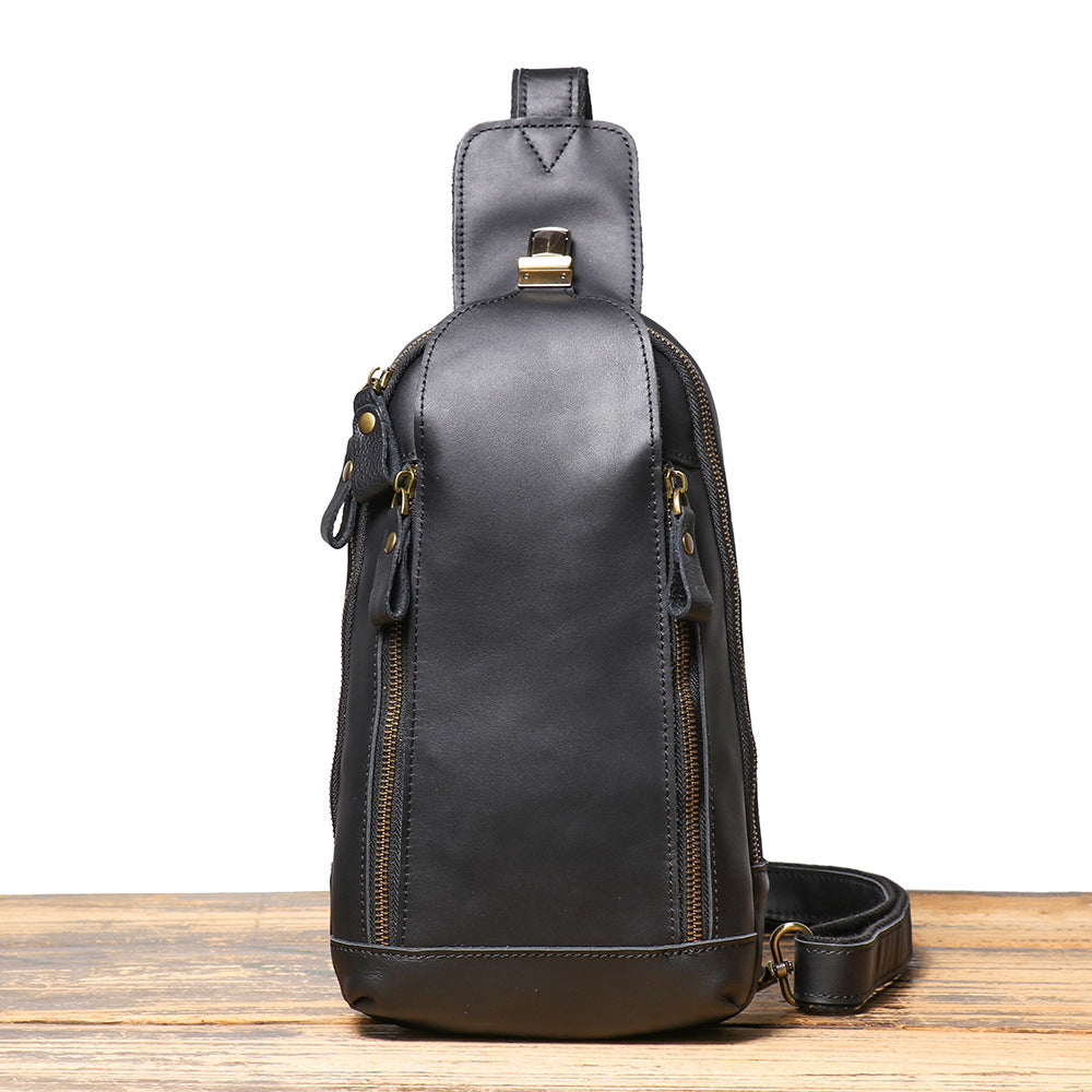 Black leather sling bag on a wooden surface with a white background
