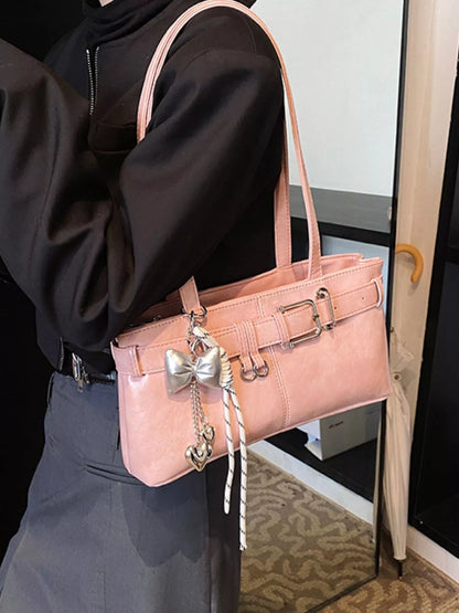 Person holding a pink handbag with decorative elements in an indoor setting
