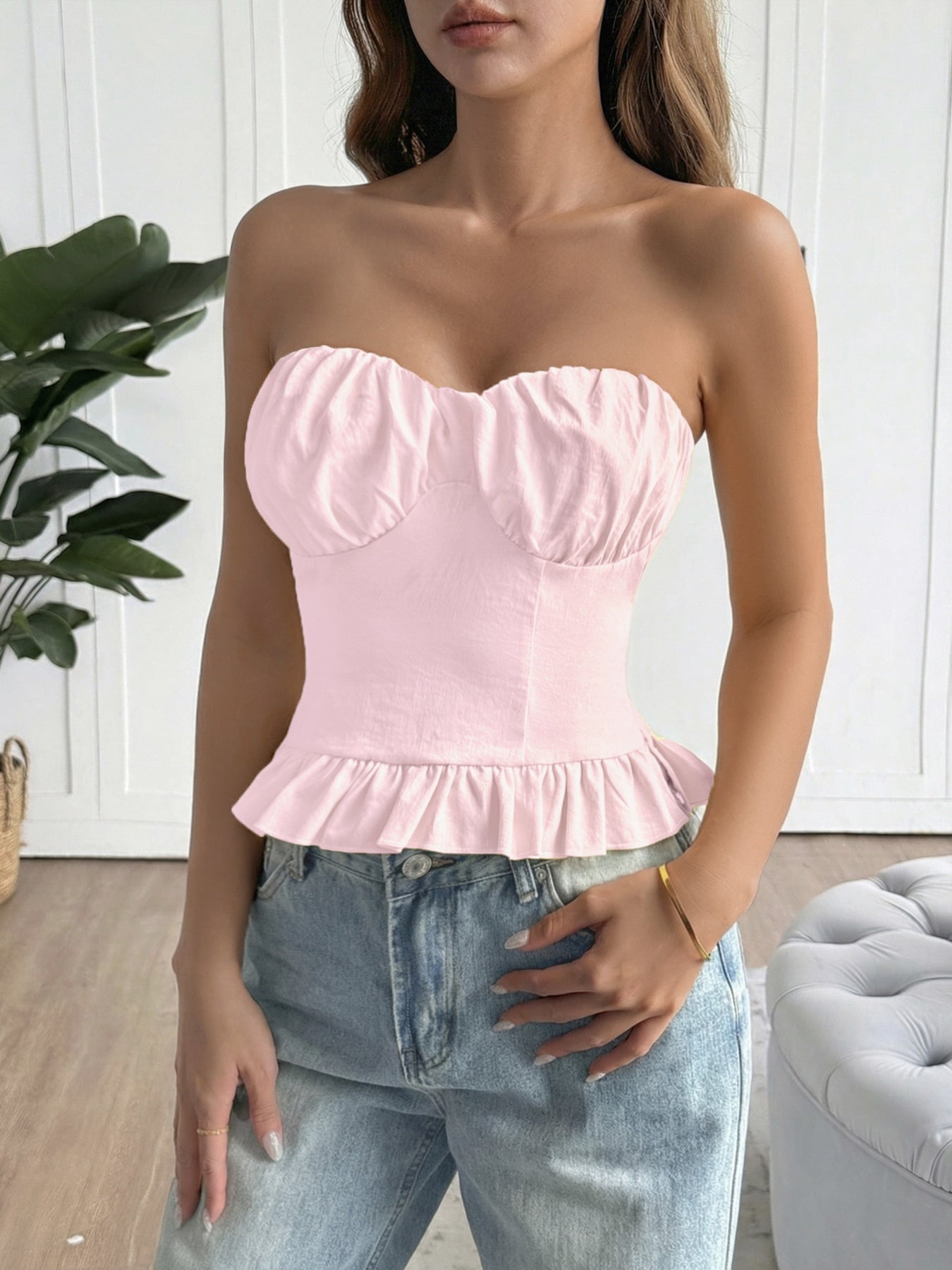 Woman wearing a pink strapless top and blue jeans indoors.