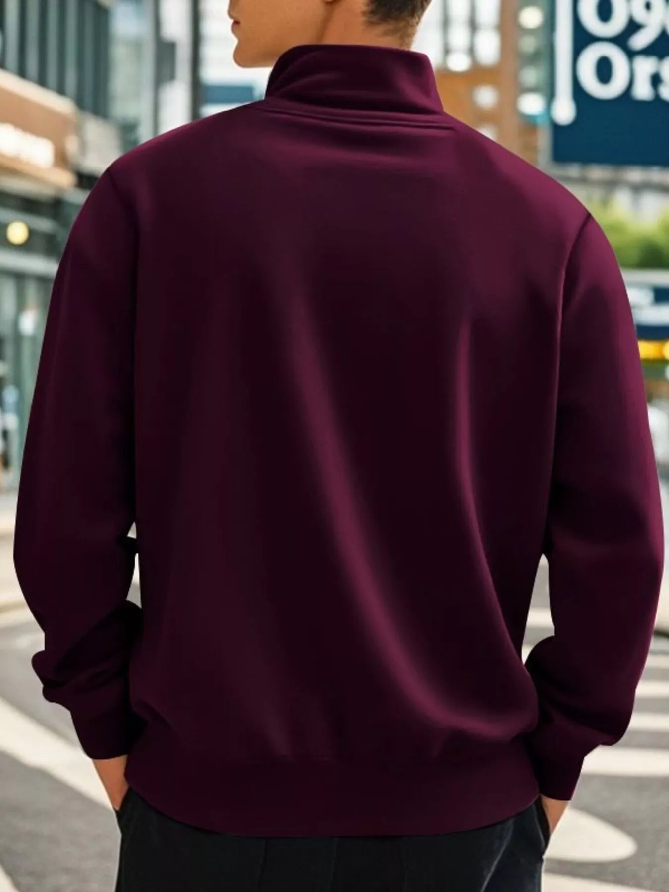 Person wearing a maroon half-zip sweatshirt on a city street.