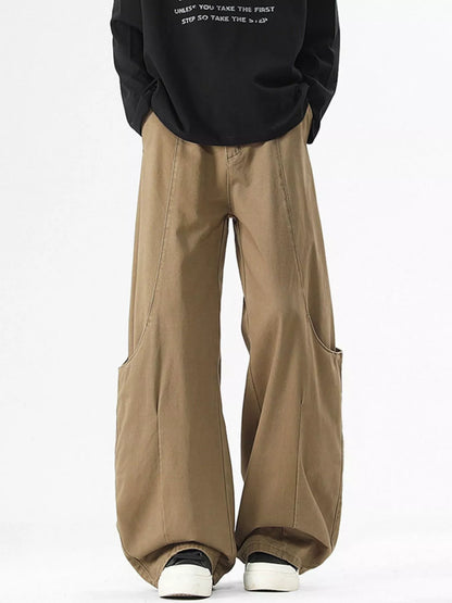 Person wearing a black sweatshirt and beige wide-leg pants on a white background