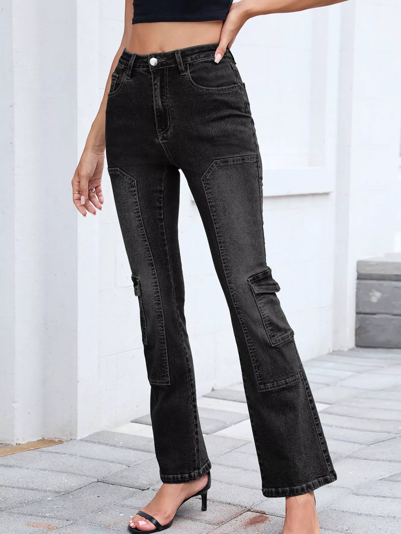 Person wearing black straight-leg jeans with a white background
