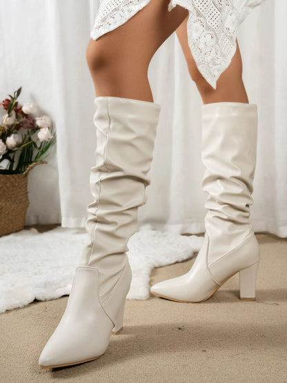 White knee-high boots worn with a white lace outfit on a neutral background