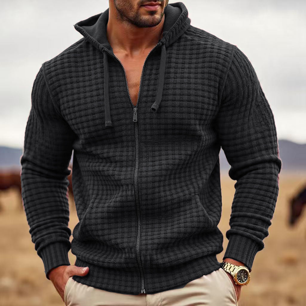 Man wearing a dark textured hoodie with a blurred natural background