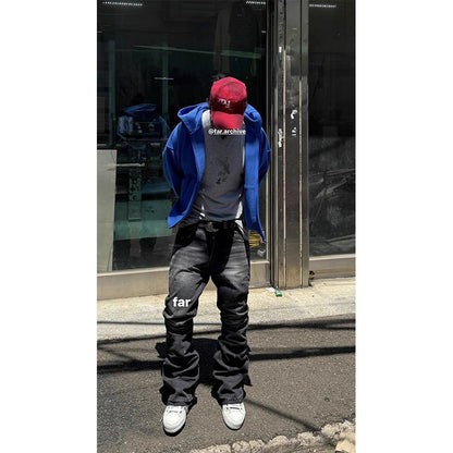 Person wearing a blue jacket, gray hoodie, black pants, and white sneakers in front of a store.