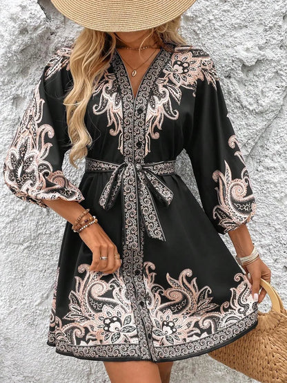 Woman wearing a black dress with white patterns against a textured wall.