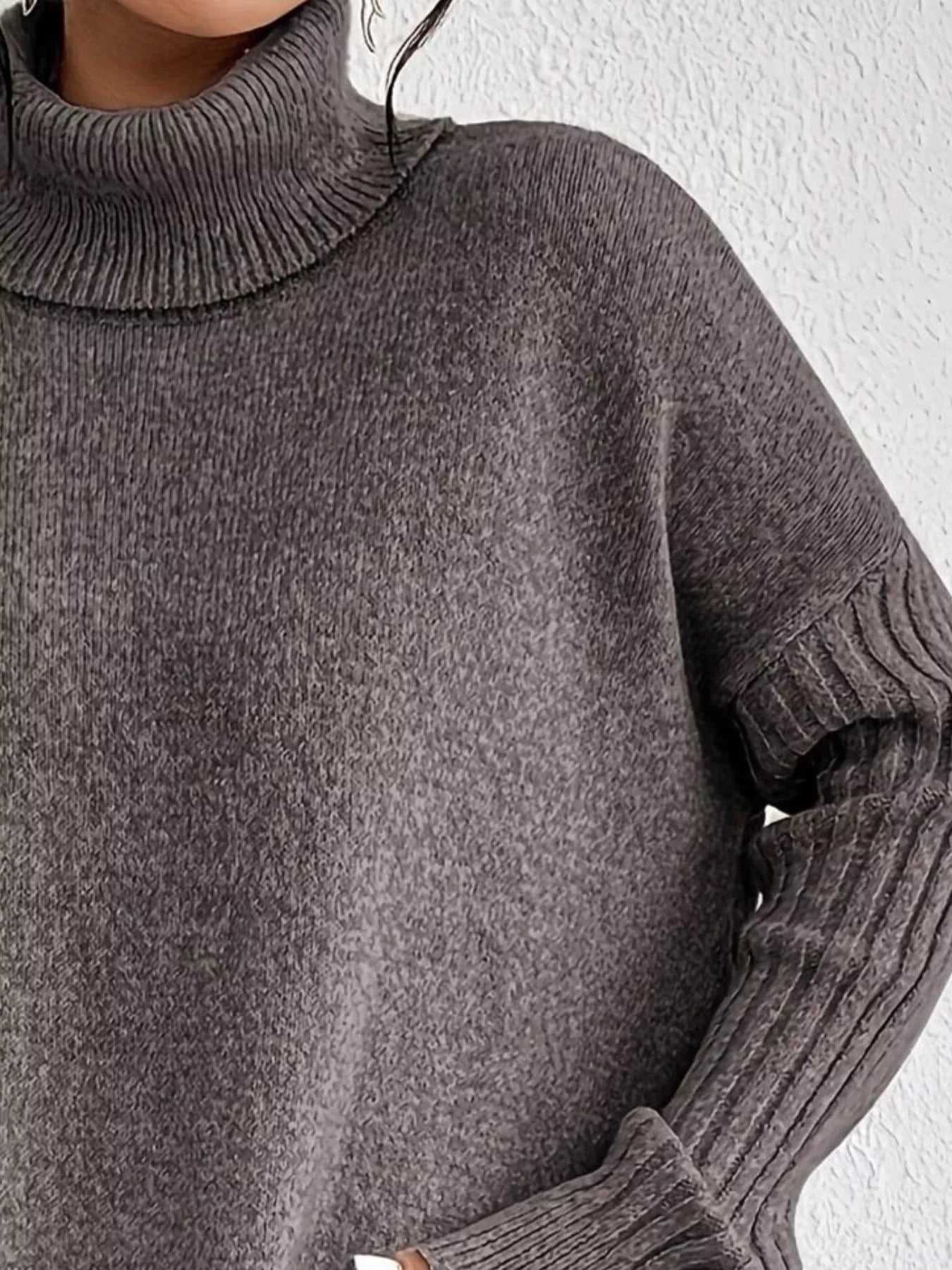 Close-up of a person wearing a gray turtleneck sweater against a white background