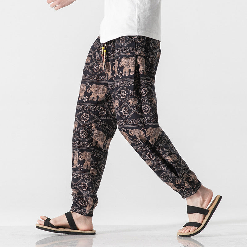 Person wearing black pants with elephant pattern on a white background
