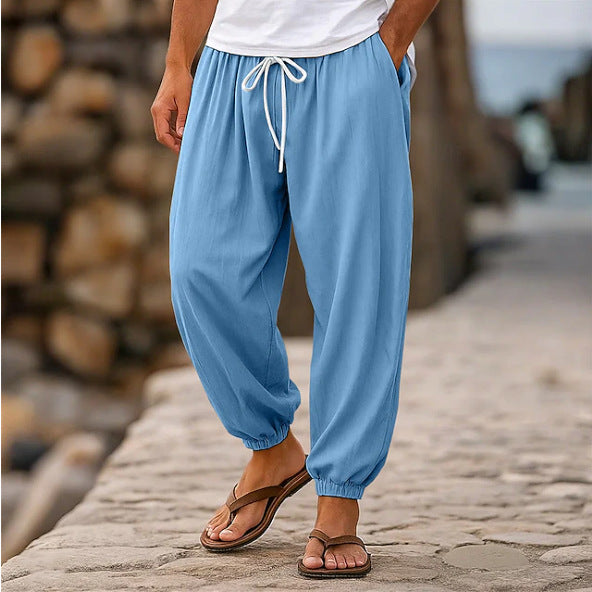 Person wearing blue pants with a white top and brown sandals on a stone path.