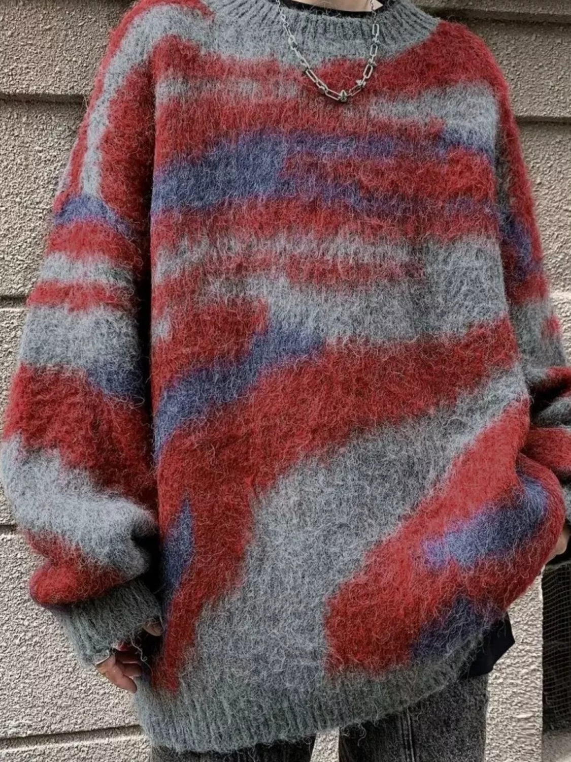 Person wearing a red, gray, and blue striped sweater against a neutral background