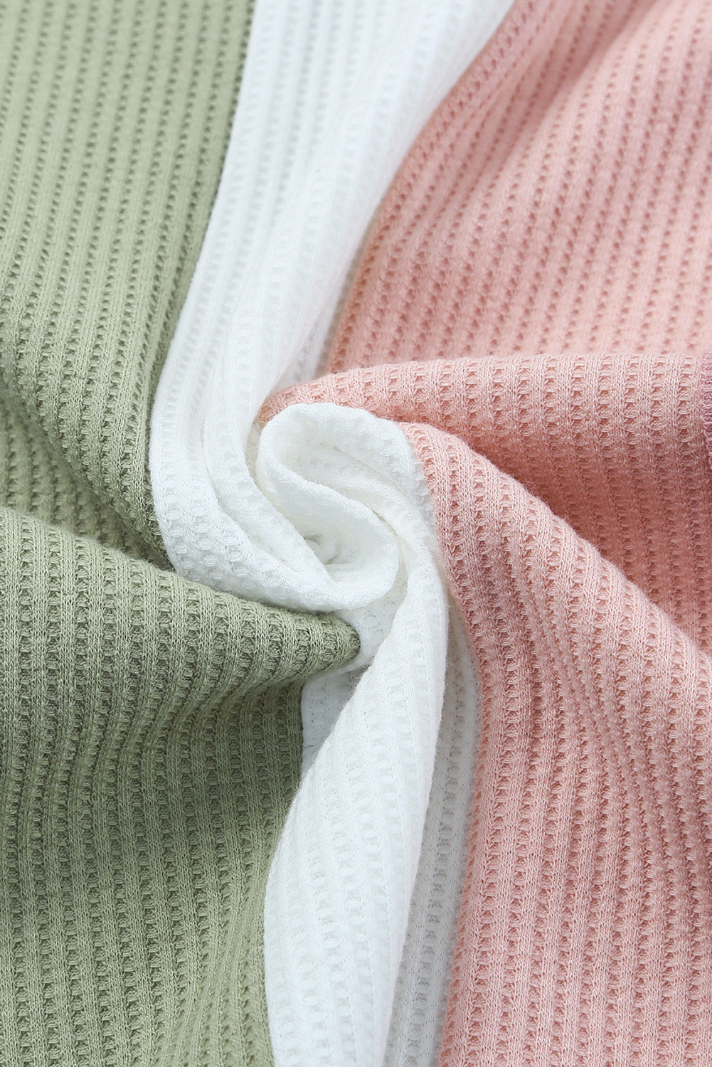 Close-up of textured fabric in green, white, and pink.