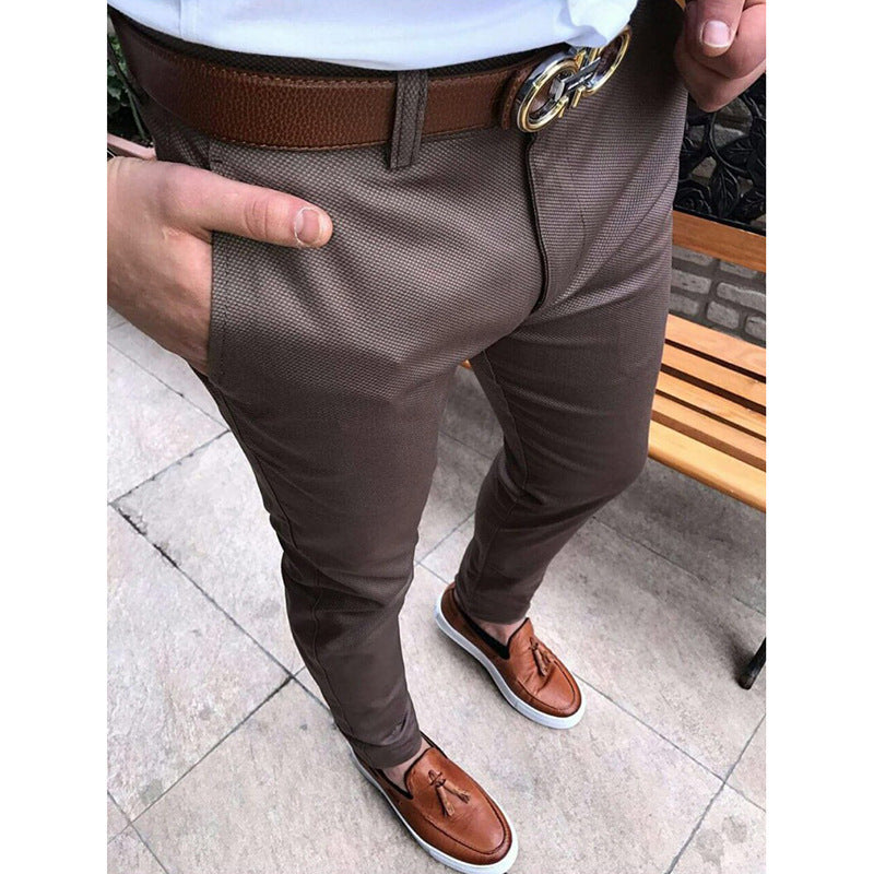 Brown pants with a belt and shoes on a tiled floor.