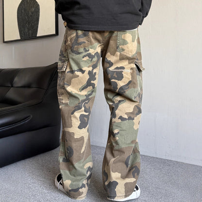 Person wearing camouflage pants in a room with a black couch and framed picture on the wall.