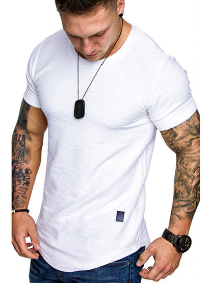 Man wearing a white t-shirt with tattoos on arms and a necklace.