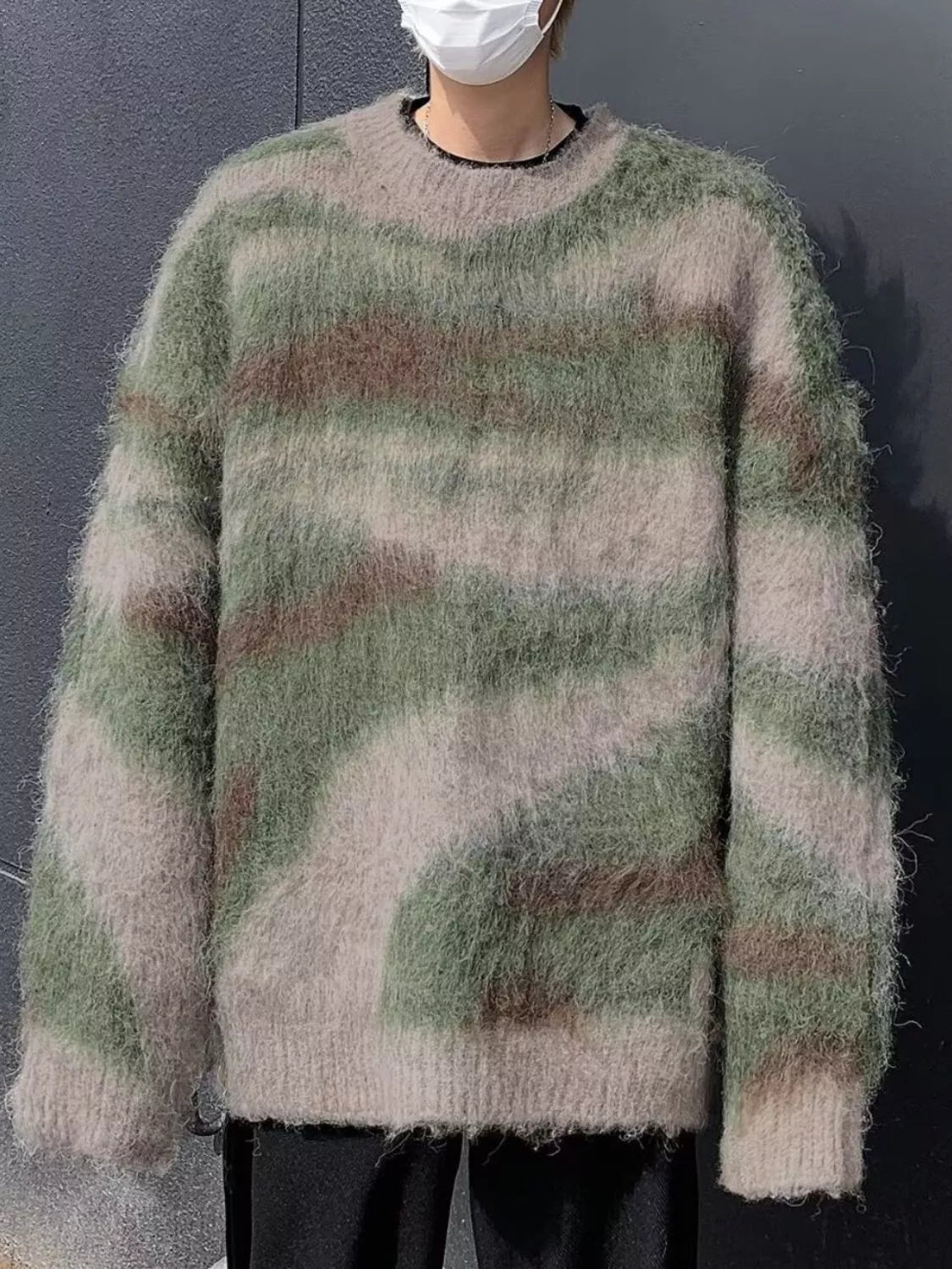 Person wearing a camouflage-patterned sweater against a dark background