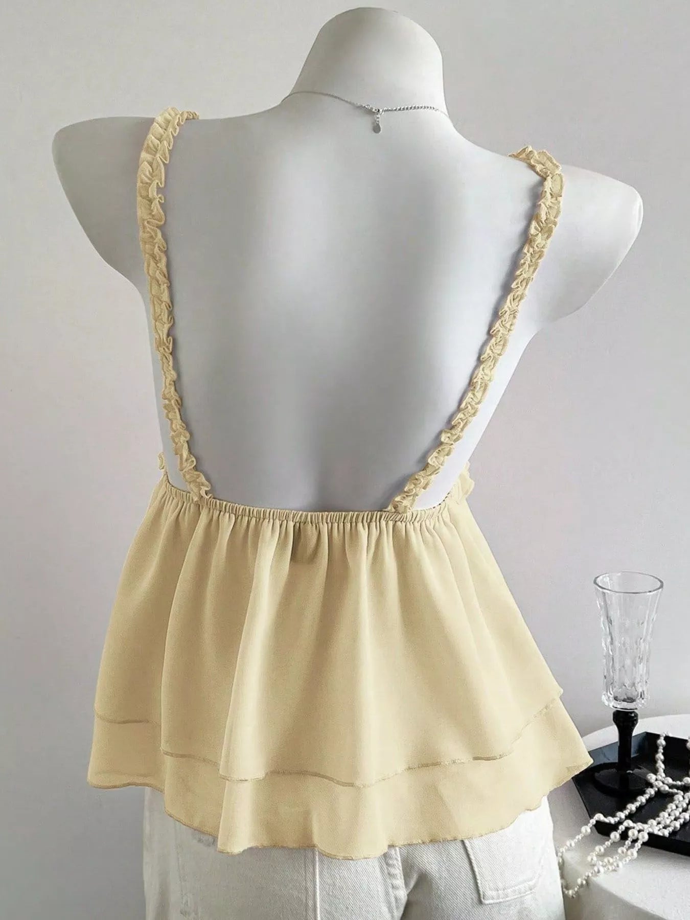Beige top with lace straps on a mannequin against a plain background