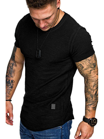 Man wearing a black t-shirt with visible tattoos on arms against a white background