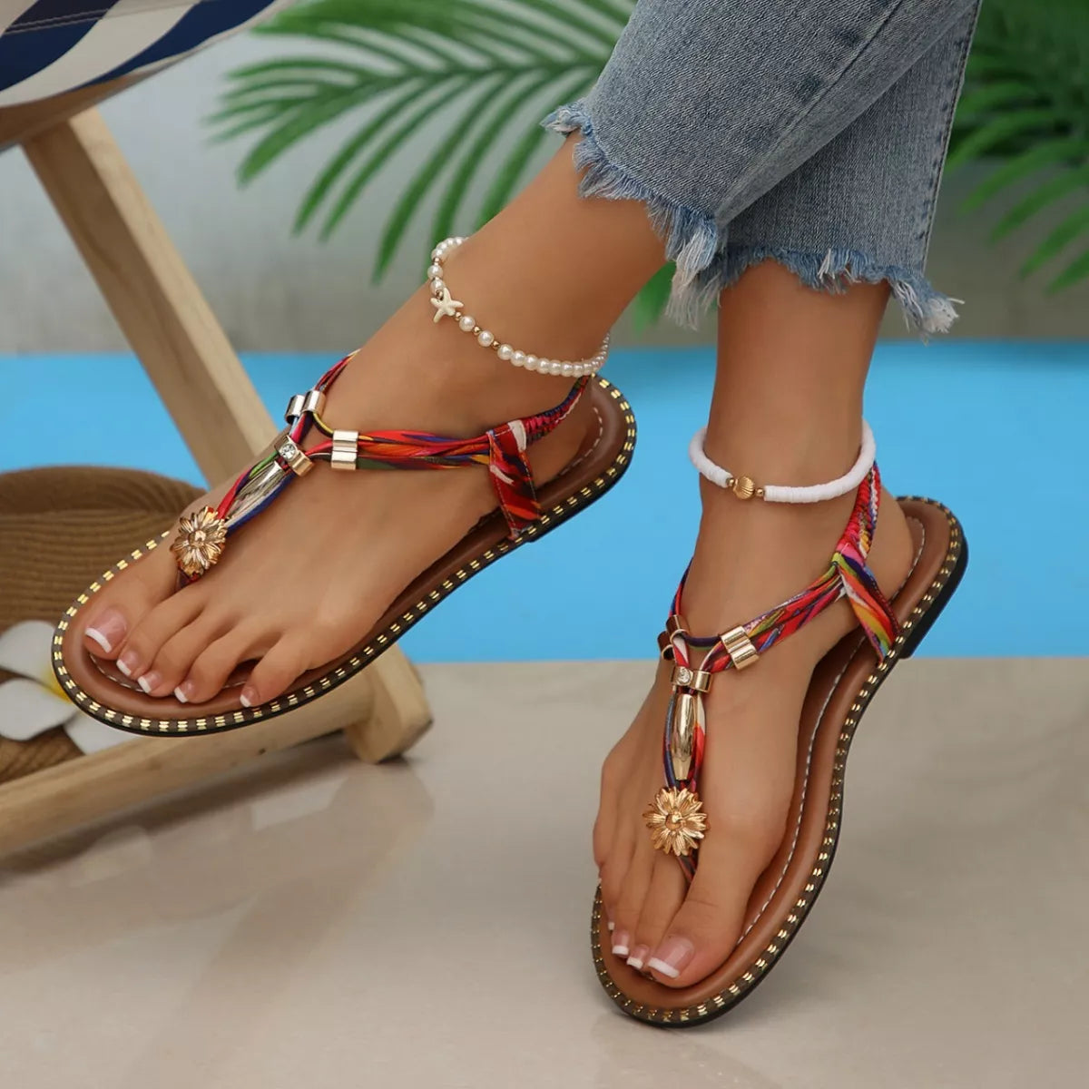 Colorful sandals with decorative straps worn by a person sitting by a pool.