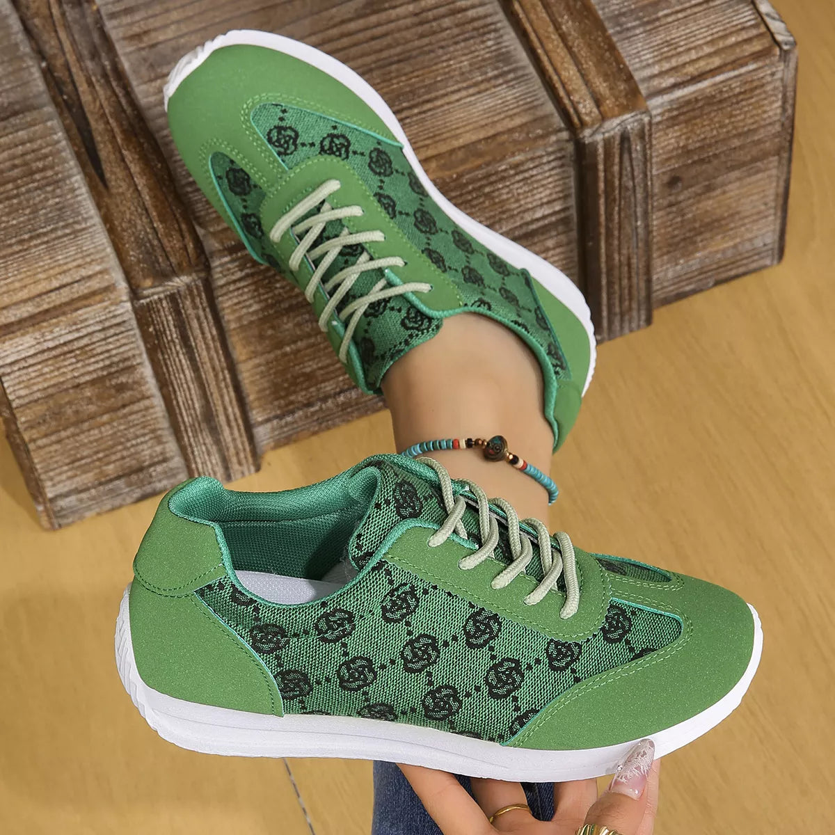 Green sneakers with black pattern worn by a person on a wooden floor.