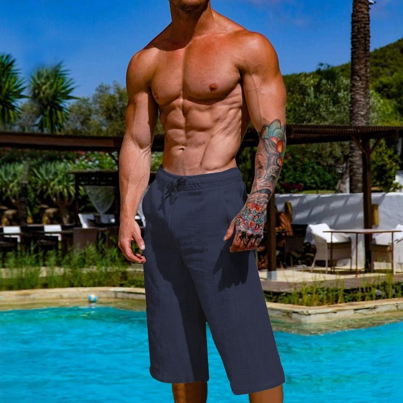 Man with tattoos standing by a pool with a scenic background