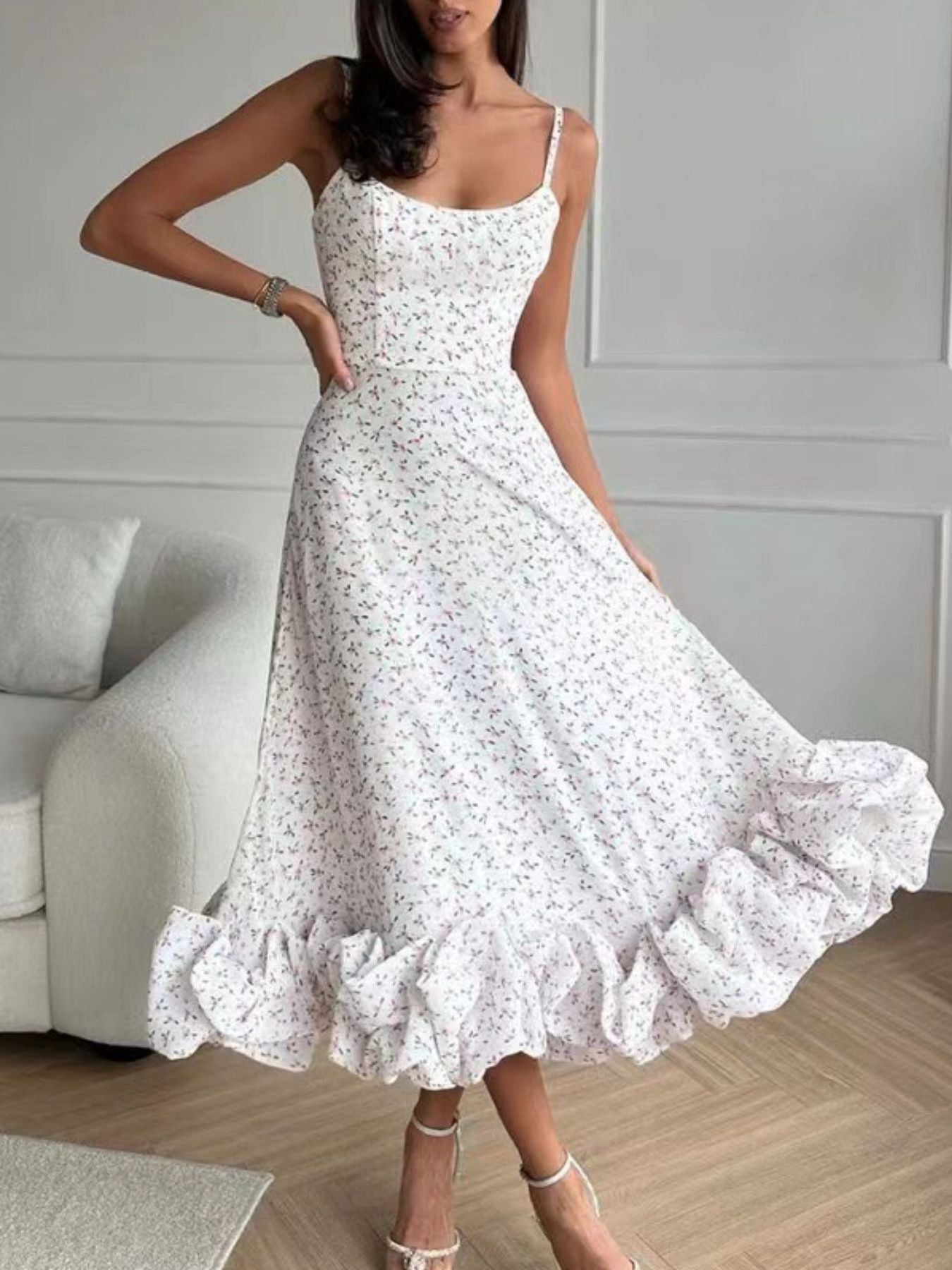 Woman wearing a white floral dress in a room with a couch and light-colored walls.