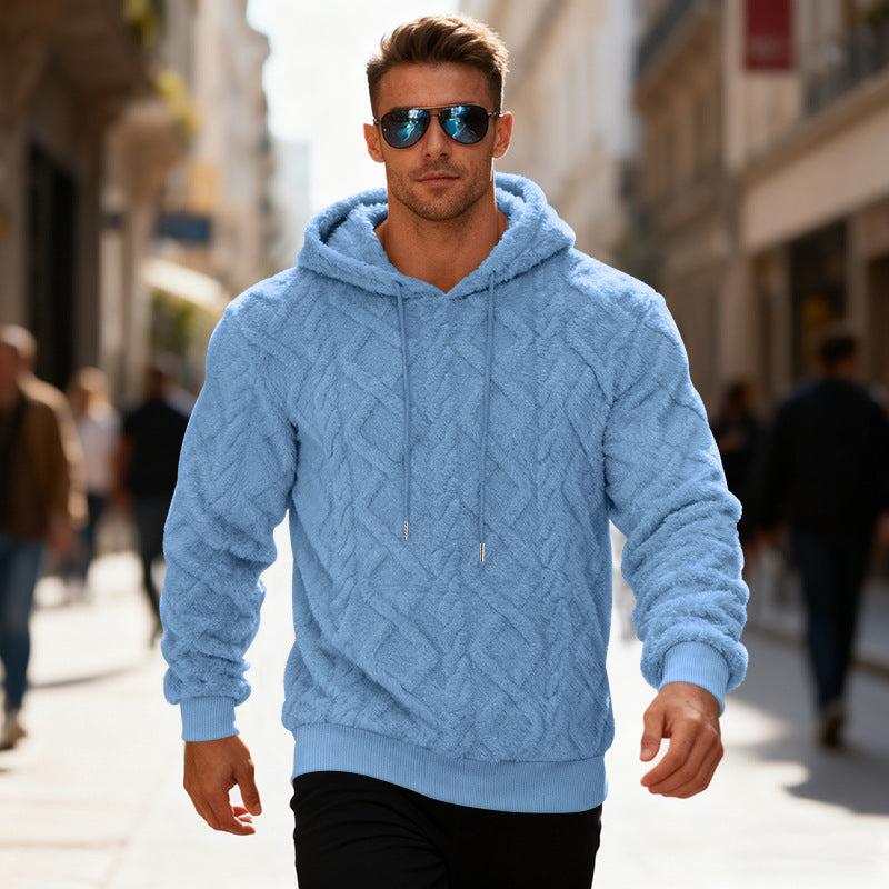 Man wearing a blue cable knit hoodie and sunglasses on a city street.