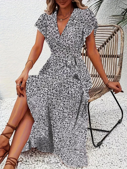 Woman wearing a floral dress sitting on a wicker chair outdoors.