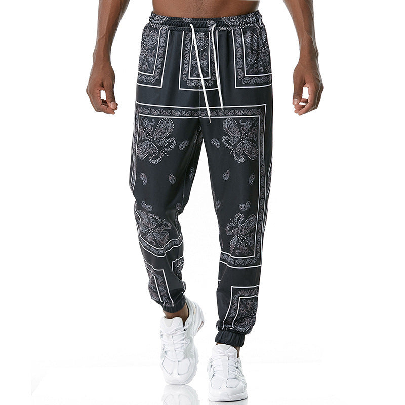 Black jogger pants with white patterns worn by a person on a white background
