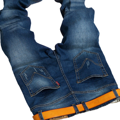 Close-up of blue jeans with an orange belt on a white background