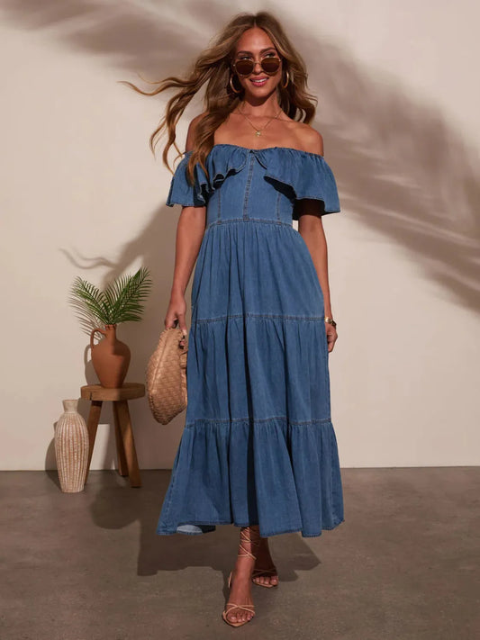 Woman wearing a blue denim dress with black accents, standing against a neutral background.