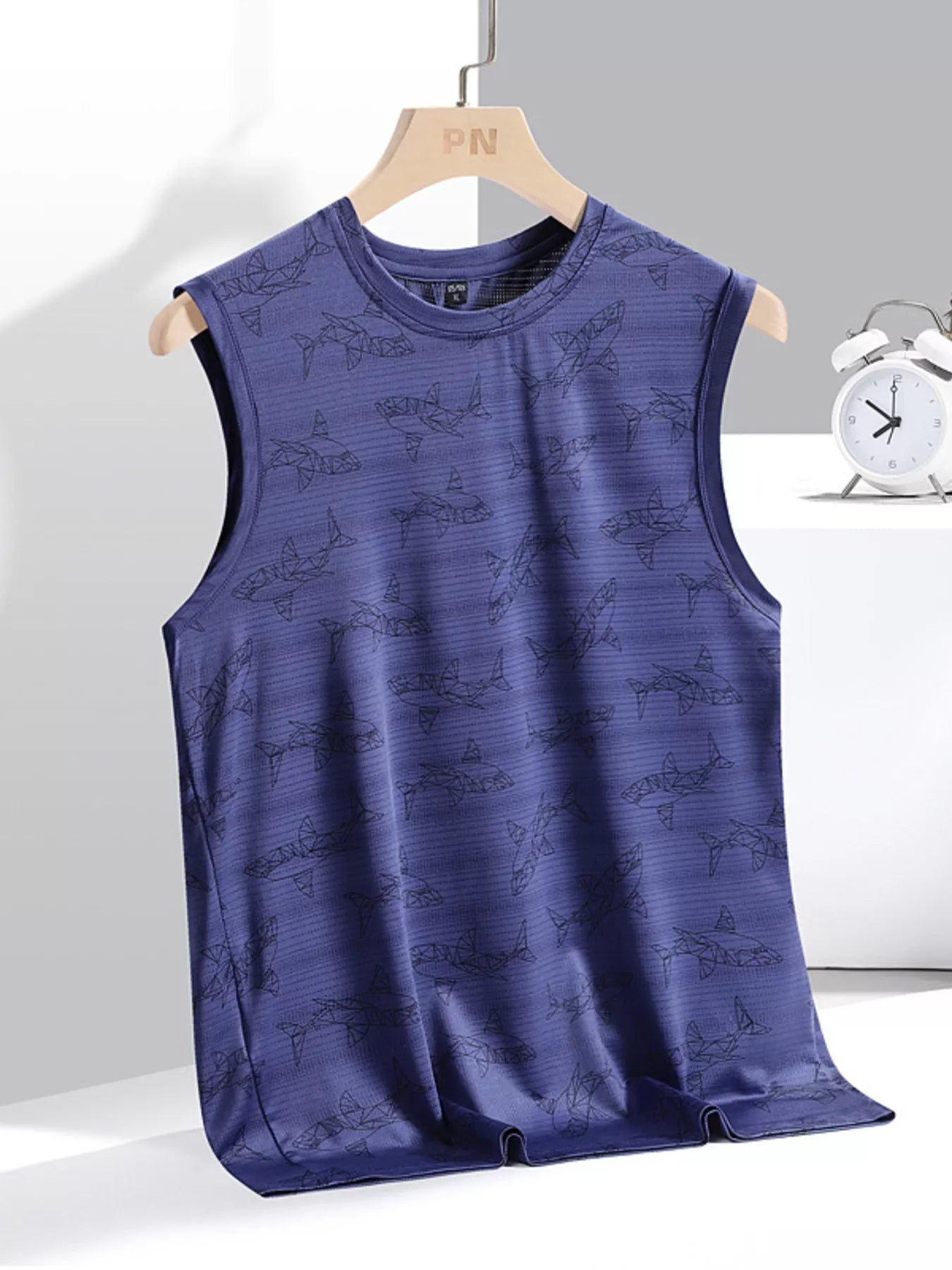 Blue sleeveless shirt with shark pattern on a hanger against a gray background