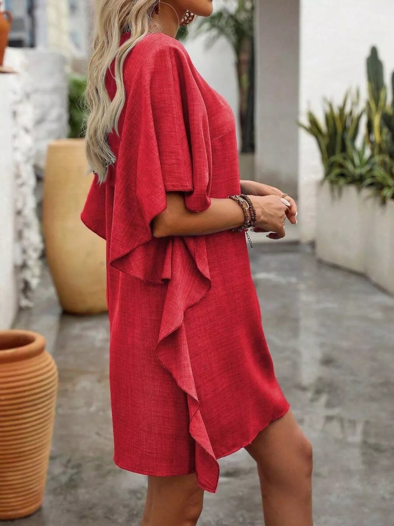 Woman wearing a red dress with ruffled layers outdoors.
