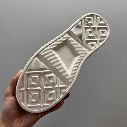 White sole with geometric pattern held against a gray background