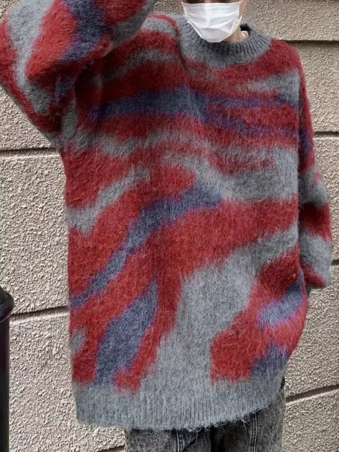 Person wearing a red, gray, and blue patterned sweater against a neutral background