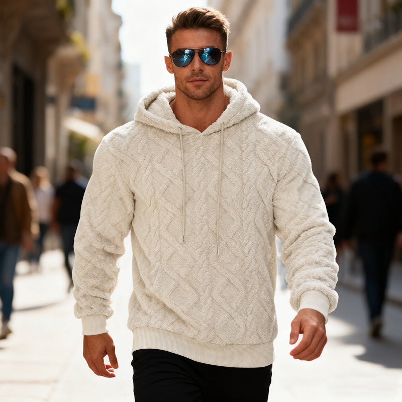 Man wearing a white cable knit hoodie and sunglasses on a city street.