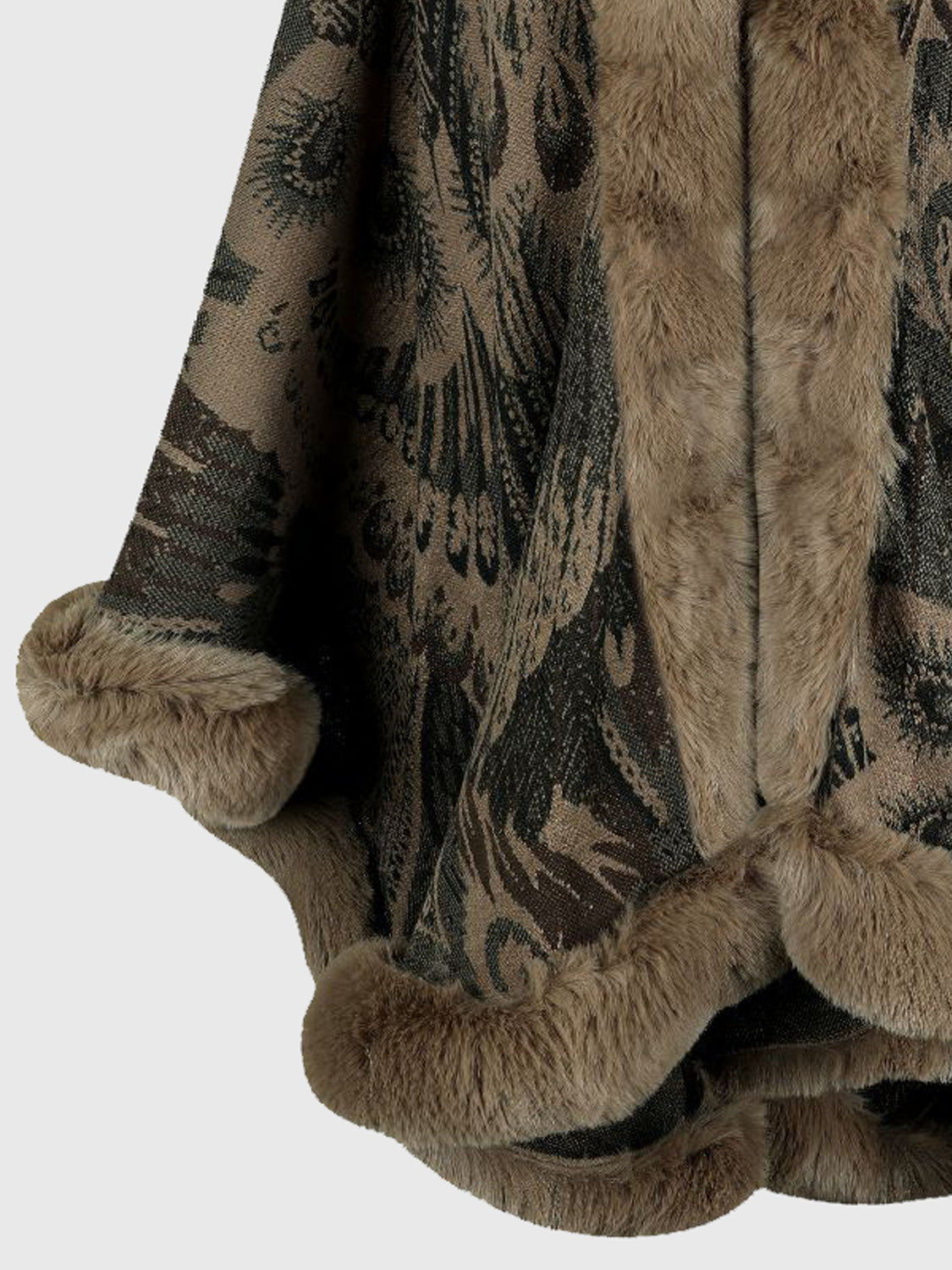 Close-up of a textured poncho with intricate patterns and fur trim on a light gray background