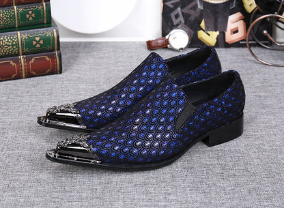 Blue patterned loafers on a gray surface with books and a watch in the background