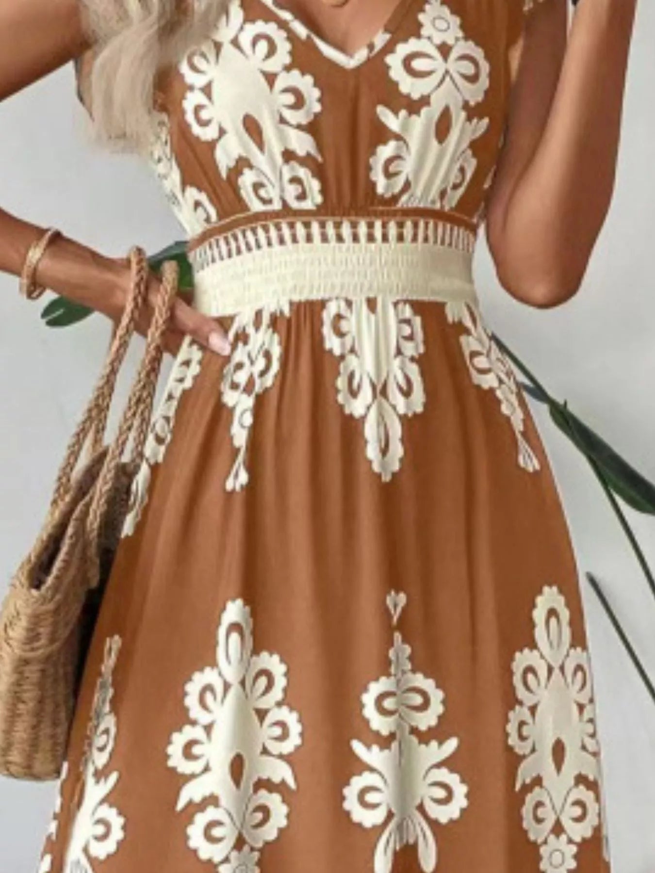 Brown dress with white lace patterns worn by a person, holding a woven bag.