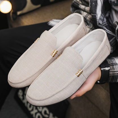 Beige loafers with gold accents held by a person wearing plaid pants.