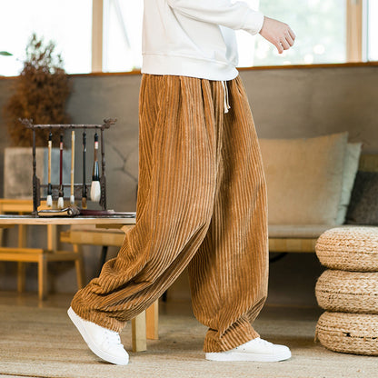 Person wearing brown pleated pants and white shoes in a living room setting.
