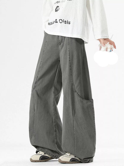 Person wearing gray wide-leg pants and a white shirt with text, holding a drink.