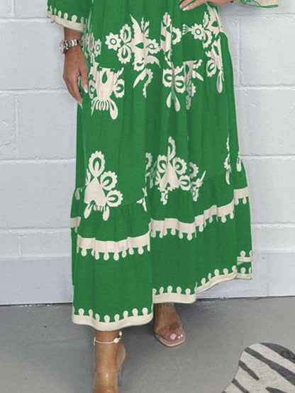 Green dress with white floral patterns worn by a person against a white brick wall.